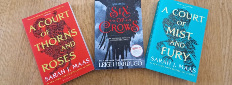 Copies of A Court of Thorns and Roses and A Court of Mist and Fury by Sarah J Maas, either side of Six of Crows by Leigh Bardugo